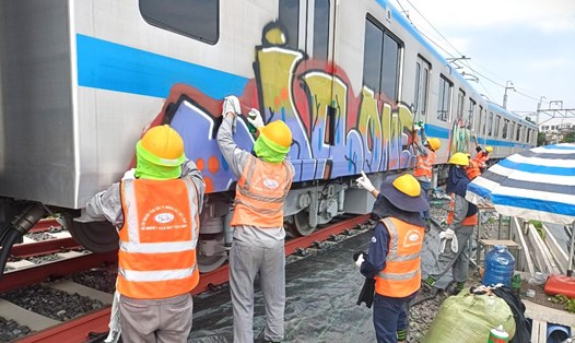 Công nhân tẩy rửa toa tàu Metro số 1 bị vẽ bậy. Ảnh: MAUR