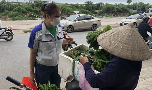 Công nhân Khu công nghiệp Quang Châu (huyện Việt Yên, tỉnh Bắc Giang) tranh thủ mua rau trên đường về phòng trọ, sau khi kết thúc giờ làm việc. Ảnh: Quế Chi