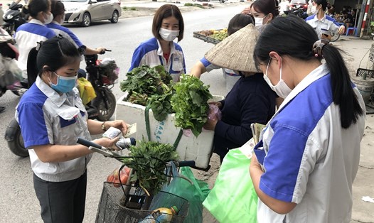 Công nhân Khu công nghiệp Quang Châu (huyện Việt Yên, tỉnh Bắc Giang) tranh thủ mua rau trên đường đi về sau buổi làm việc đêm. Ảnh: Quế Chi