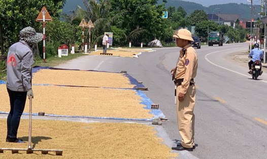 Cảnh sát giao thông huyện Can Lộc nhắc nhở người dân xã Sơn Lộc phơi lúa trên tuyến quốc lộ 15B tiềm ẩn mất an toàn giao thông. Ảnh: Trần Tuấn