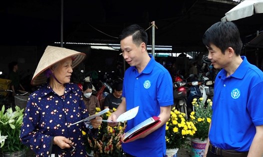 Cán bộ BHXH huyện Phú Lương phát tờ rơi tuyên truyền chính sách BHXH tới các hộ gia đình tại chợ xã Phẫn Mễ. Ảnh: BHXH tỉnh Thái Nguyên