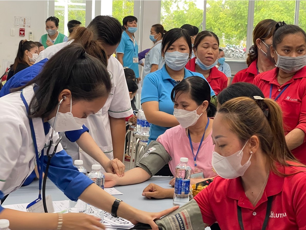Các công nhân lao động đang được đo huyết áp trước khi khám bệnh và cấp thuốc. Ảnh: Cẩm Tú