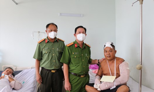 Đại tá Diệp Văn Thế (ở giữa) – Phó Giám đốc Công an tỉnh Kiên Giang thăm hỏi và tặng tiền cho anh Phạm Hoài Ân đang nằm điều trị vết thương tại Trung tâm y tế huyện An  Biên. Ảnh: Công an cung cấp
