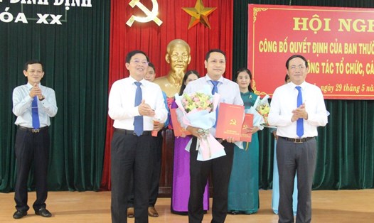 Ông Hà Duy Trung (hàng đầu, đứng giữa), nhận quyết định và hoa chúc mừng từ lãnh đạo Bình Định. Ảnh: Nguyễn Ngọc