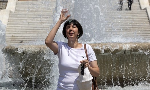 Một phụ nữ dội nước vào đầu trong đợt nắng nóng ở Athens, Hy Lạp. Ảnh: Xinhua