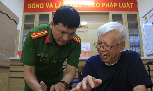 Trung tá Nguyễn Anh Tuấn hướng dẫn người dân đăng kí tài khoản định danh điện tử. Ảnh: Khánh An