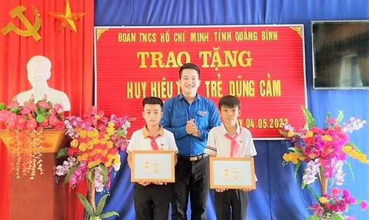 Đại diện lãnh đạo Tỉnh đoàn Quảng Bình trao huy hiệu “Tuổi trẻ dũng cảm” cho 2 em học sinh. Ảnh: Cộng tác viên