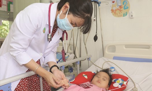 Bác sĩ Trần Ngọc Lưu - Khoa Nhiễm, Bệnh viện Nhi Đồng 2 thăm khám cho trẻ bị tay chân miệng. Ảnh: Hạ Mây