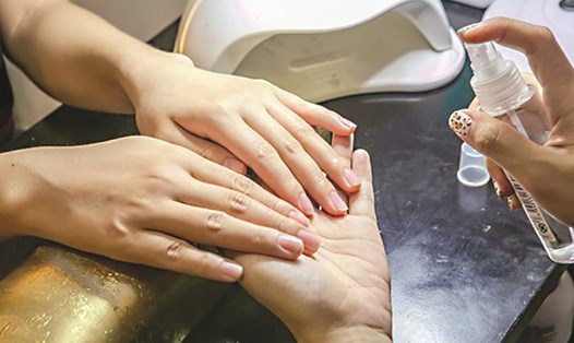 Trước khi sử dụng máy làm khô móng chứa tia UV nên dưỡng da tay và dùng gang tay bảo vệ da. Ảnh: Thanh Hương