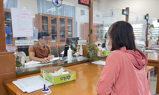 Cán bộ Bảo hiểm xã hội thành phố Hà Nội hướng dẫn người dân làm thủ tục liên quan đến chế độ bảo hiểm xã hội. Ảnh: Hà Anh
