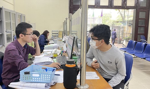 Cán bộ BHXH thành phố Hà Nội trả lời thắc mắc của người dân về chế độ BHXH tự nguyện. Ảnh: Hà Anh