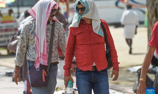 Người dân ra đường trùm kín chống nắng nóng ở Ấn Độ. Ảnh: Xinhua