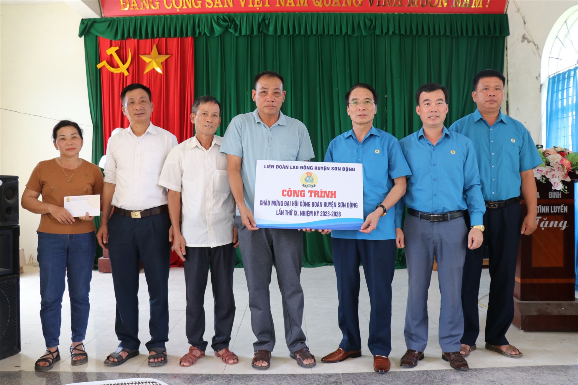 Thường trực Liên đoàn Lao động huyện Sơn Động trao biển Công trình Thắp sáng đường quê. Ảnh: Trà My