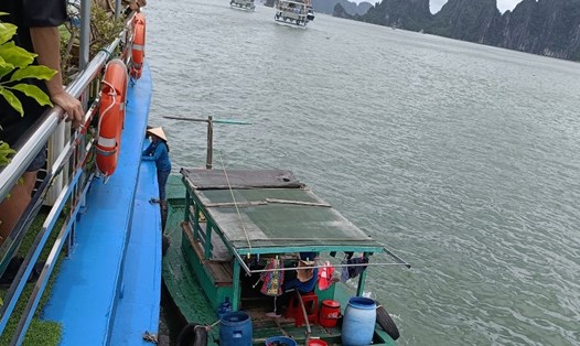 Một chiếc tàu gỗ cập vào mạn tàu du lịch trên vịnh Hạ Long để mời chào du khách mua hàng ngày 21.6.2023. Ảnh: Nguyễn Hùng