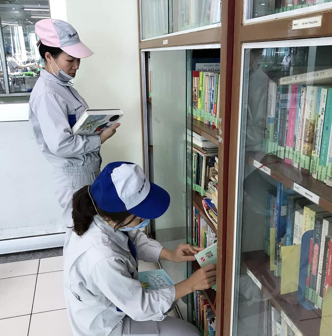 Công nhân hào hứng với tủ sách công đoàn đặt ngay tại nhà ăn công ty. Ảnh: Synztec