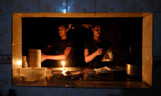 Nhân viên một quán ăn làm việc dưới ánh nến do mất điện ở Dhaka, Bangladesh. Ảnh: AP