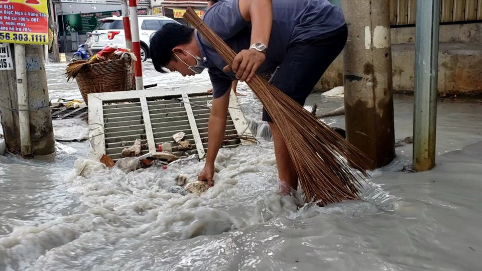 Người dân khơi thông cống để thoát nước do ngập trên đường Đồng Khởi. Ảnh: Hà Anh Chiến