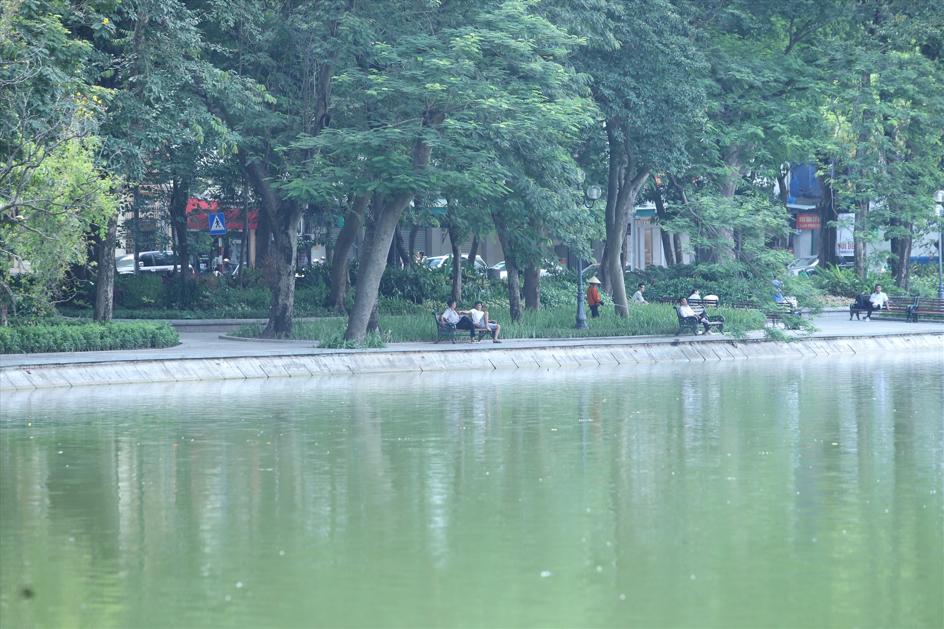 Du khách tránh nắng trong khu vực rợp bóng cây ở ven hồ Gươm. Ảnh: Vĩnh Hoàng 