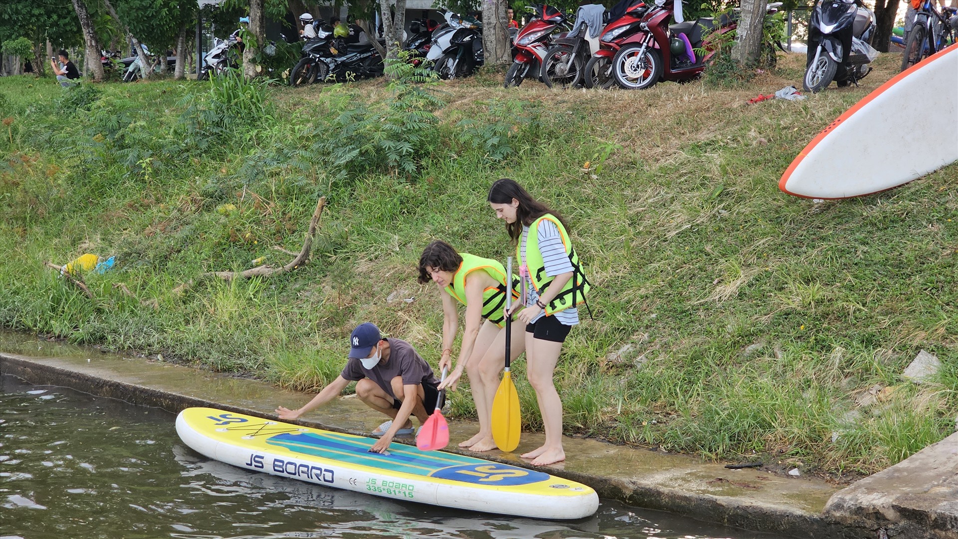 Những du khách nước ngoài hòa mình vào đám đông người địa phương, thích thú với trải nghiệm chèo SUP trên sông Hương. 