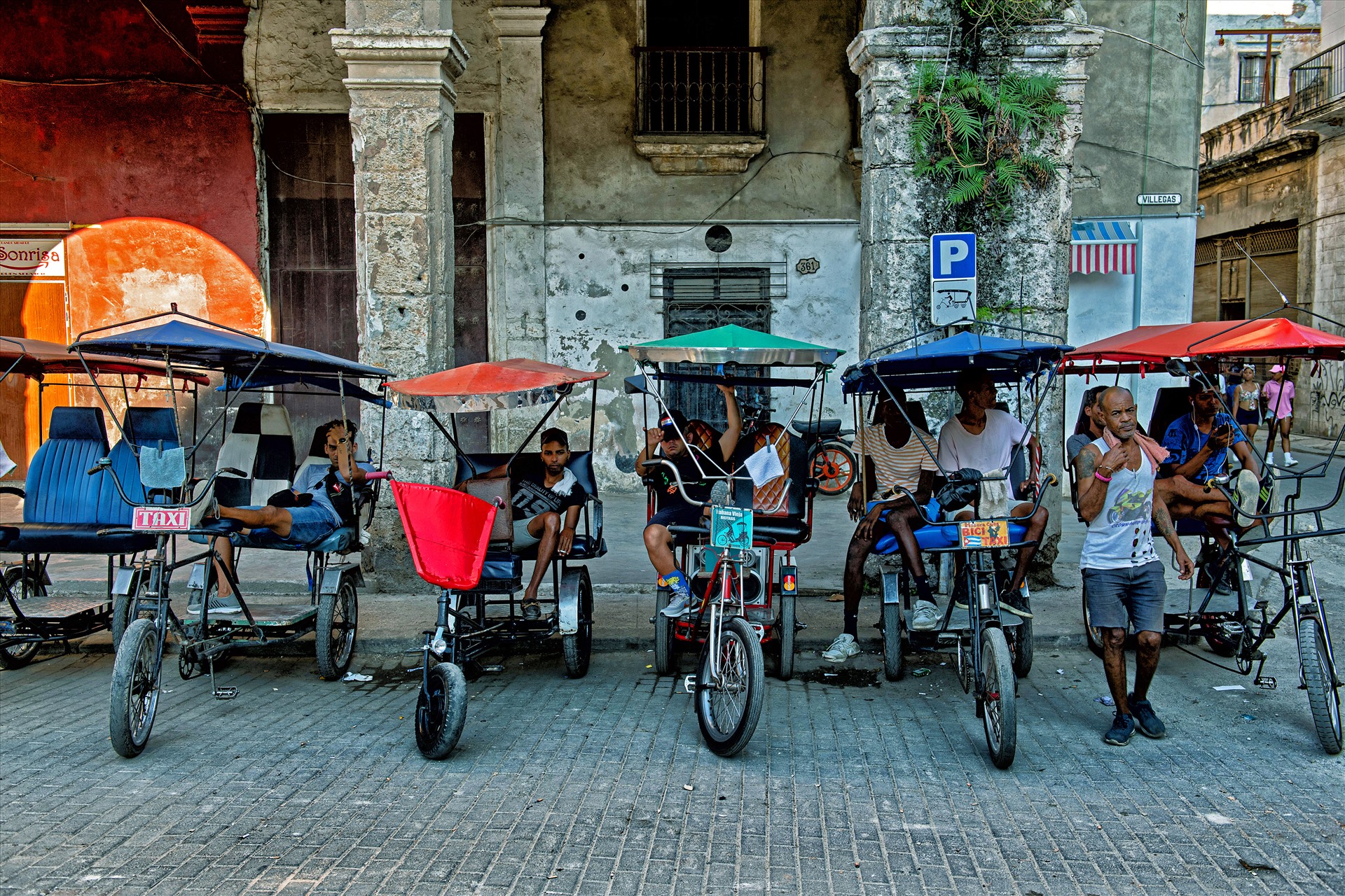 Những người lái xe tuk tuk đang chờ khách ở một con phố cổ ở La Habana, thủ đô Cuba. 