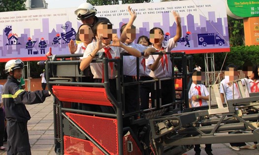 Học sinh tham gia trải nghiệm thoát nạn sử dụng xe thang cùng các chiến sĩ cảnh sát phòng cháy chữa cháy. Ảnh: Hương Giang