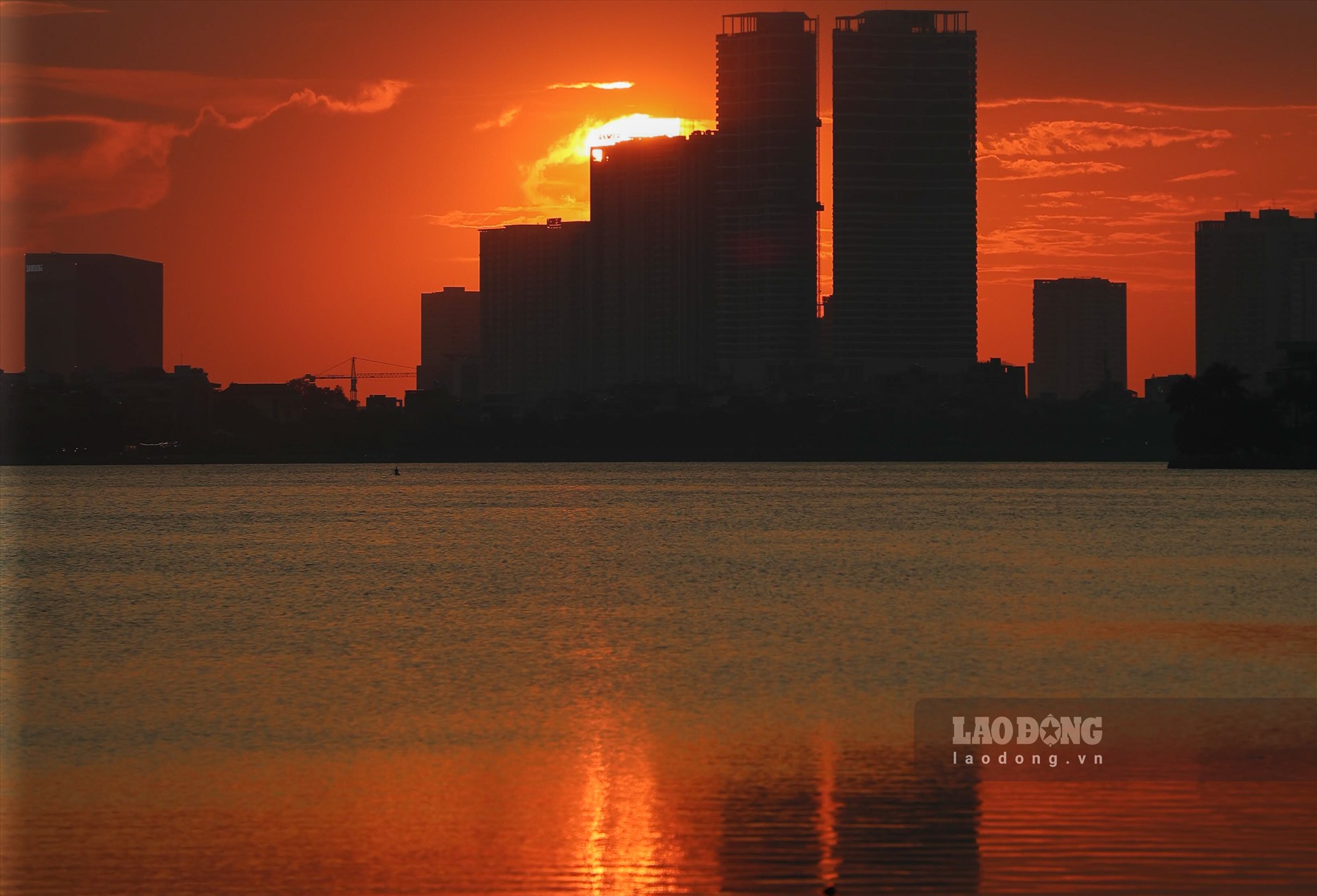 Mặt trời khuất sau các tòa nhà, đường chân trời cũng trở nên đỏ rực đổ bóng xuống mặt hồ.