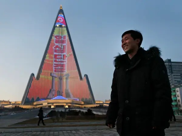 Nhà thiết kế Kim Yong Il cạnh buổi trình diễn ánh sáng ở mặt tiền khách sạn Ryugyong. Ảnh: Dita Alangkara/AP