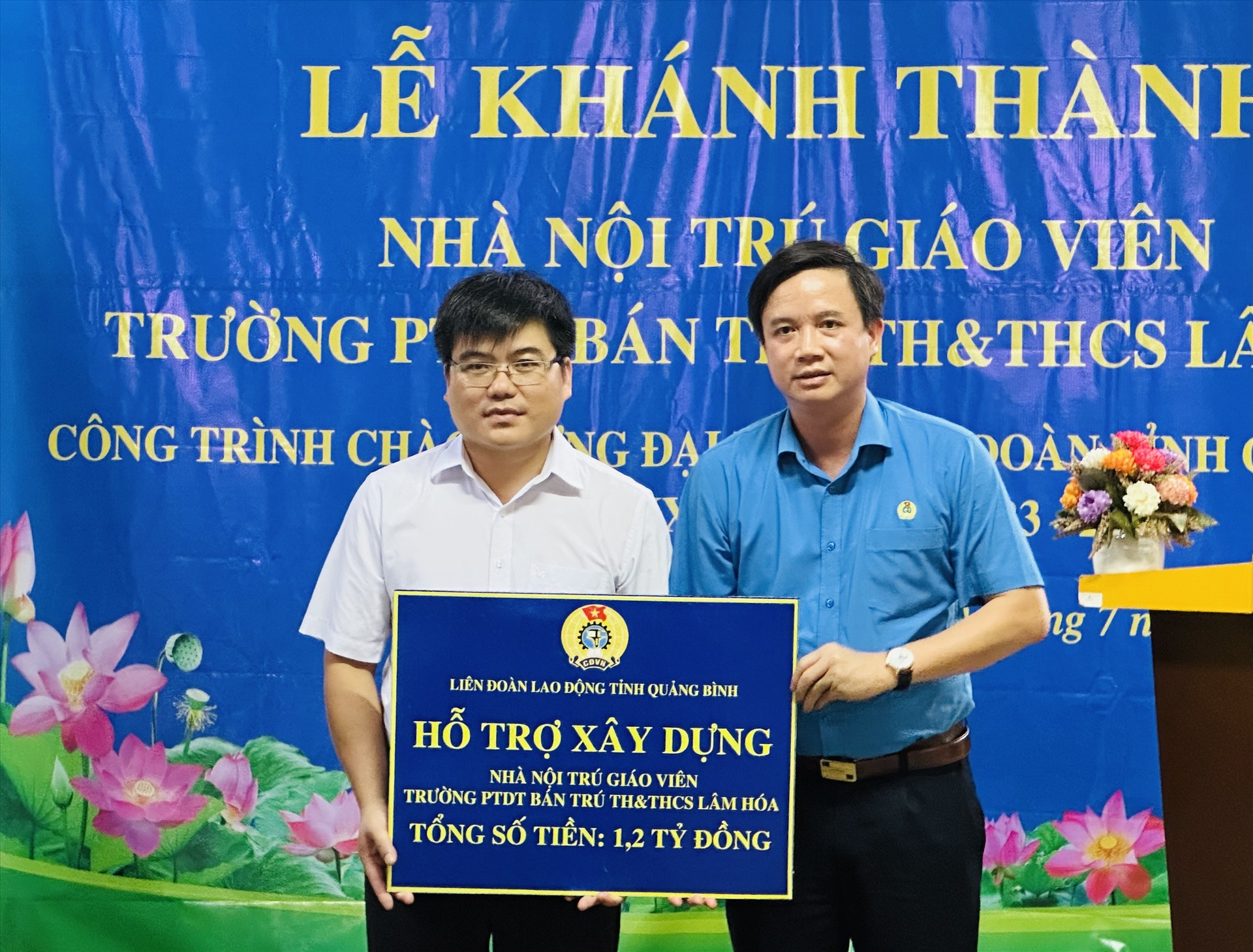 Chủ tịch LĐLĐ Quảng Bình Phạm Tiến Nam trao tượng trưng hỗ trợ cho lãnh đạo nhà trường. Ảnh: Lê Phi Long