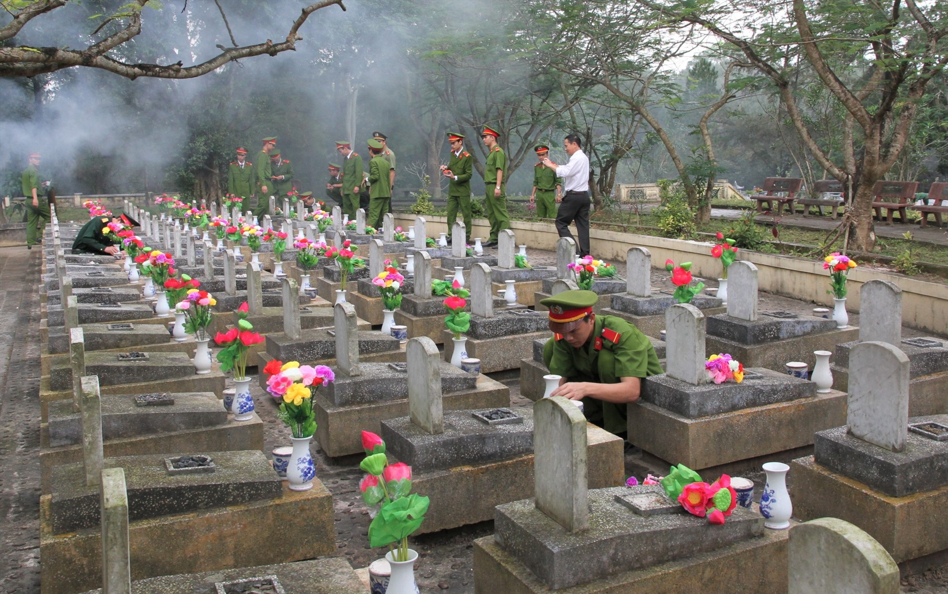 Gắn bình và hoa lên các ngôi mộ ở nghĩa trang liệt sĩ tại tỉnh Quảng Trị. Ảnh: Hưng Thơ.