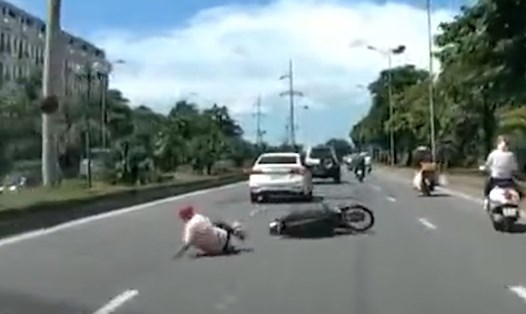 Người và xe máy ngã ra đường sau va chạm. Ảnh cắt từ clip