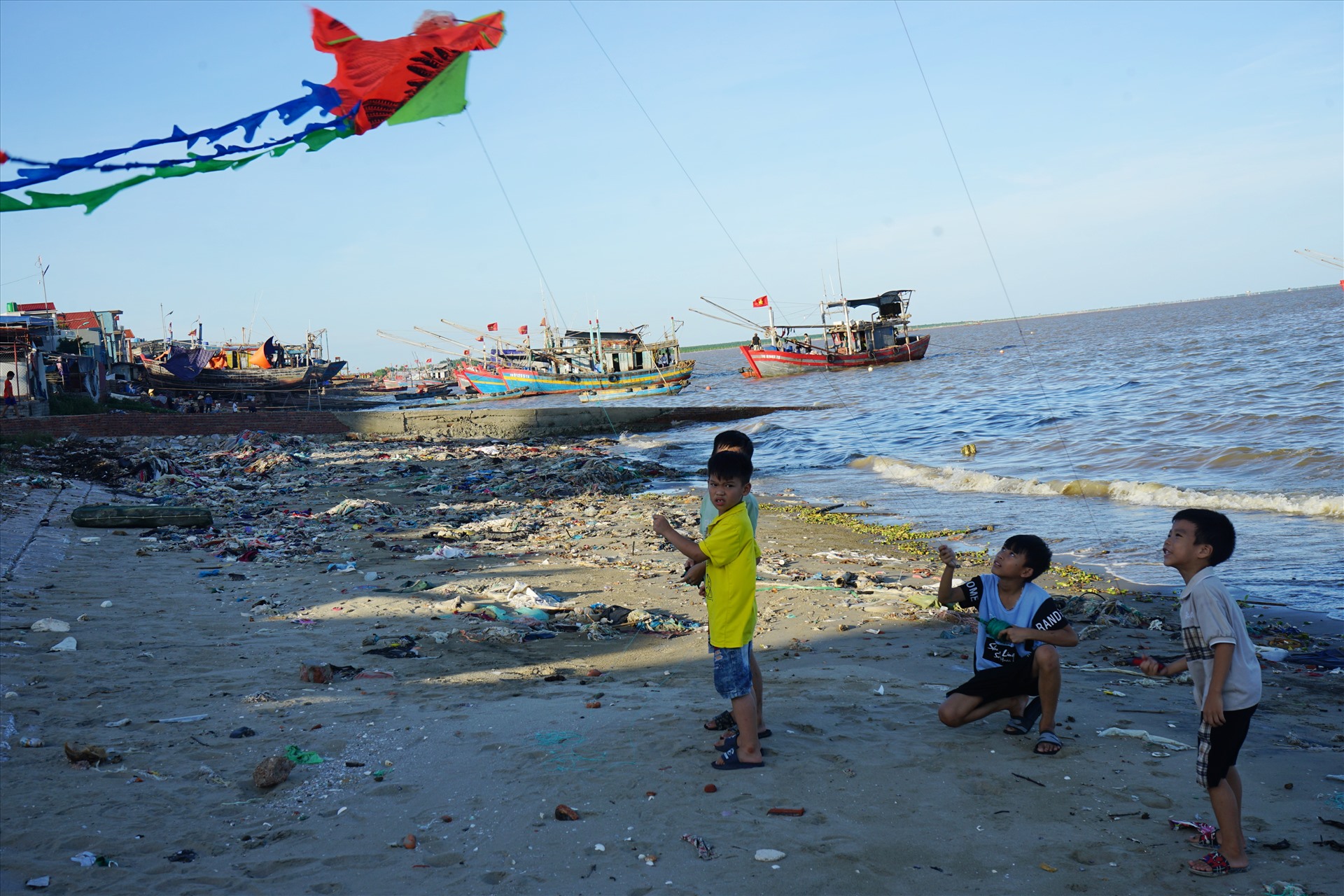 Nhiều đứa trẻ chơi đùa trên bờ biển ngập rác. Ảnh: Quách Du