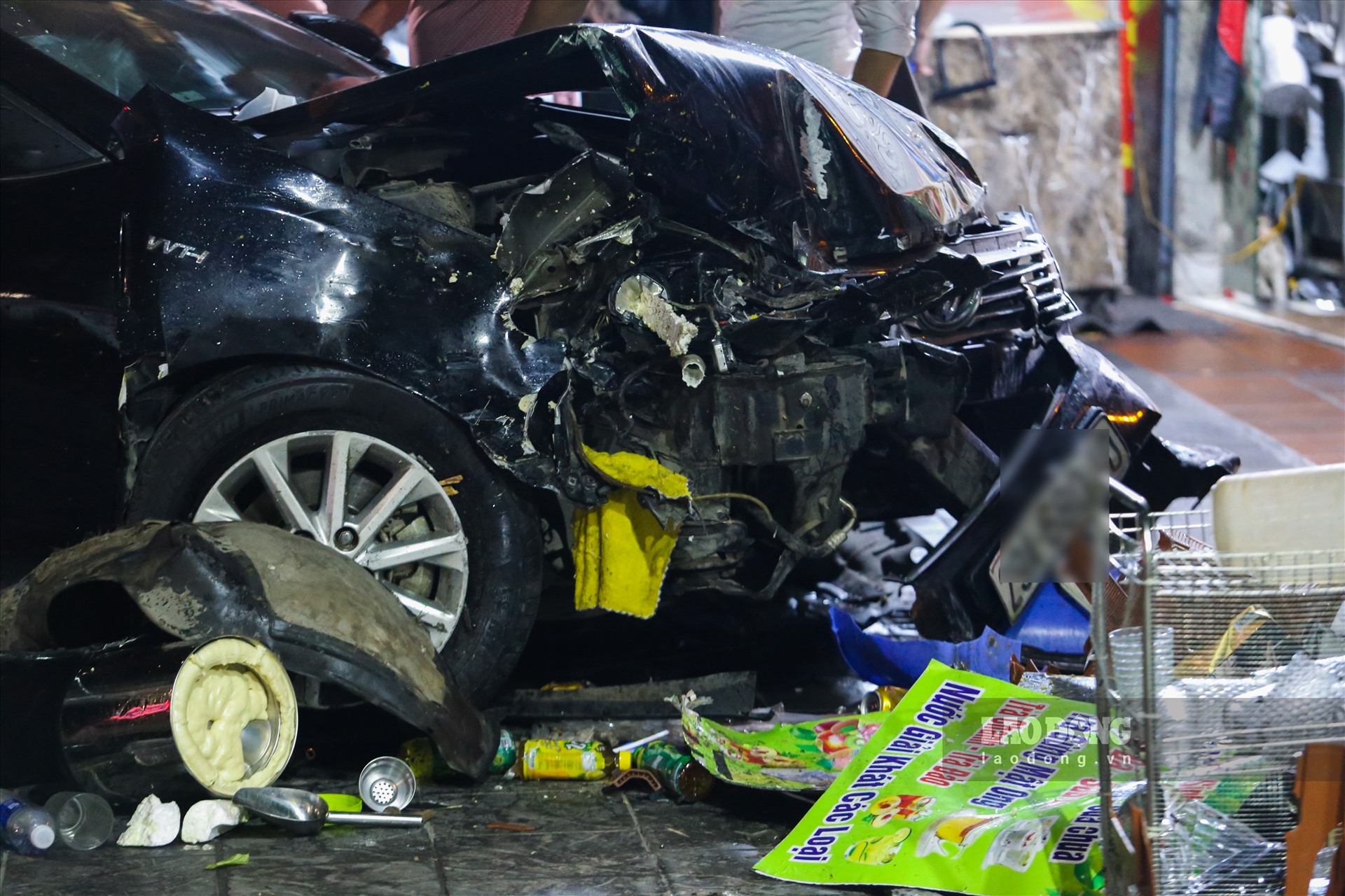Ôtô sau khi tông trúng người đã tông tiếp vào cột đèn chiếu sáng và cửa cuốn nhà dân khiến phần đầu xe hư hỏng nặng.