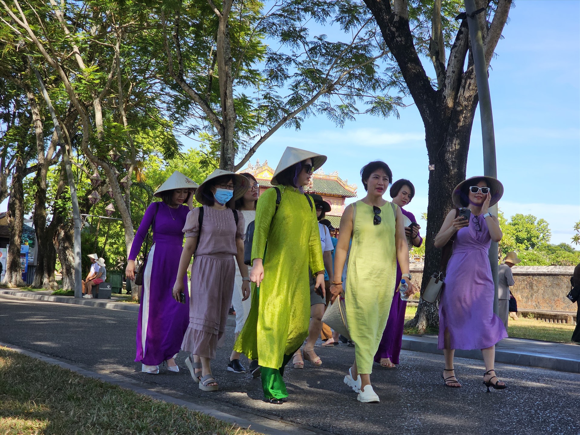 Những người phụ nữ Việt khoác lên mình tà áo dài truyền thống, thướt tha dưới hàng cây xanh Hoàng thành.