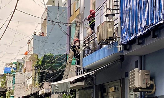 Lực lượng chức năng dùng thang tiếp cận sân thượng đưa người đàn ông bị điện giật ở Gò Vấp xuống đất. Ảnh: Nguyên Hoàng
