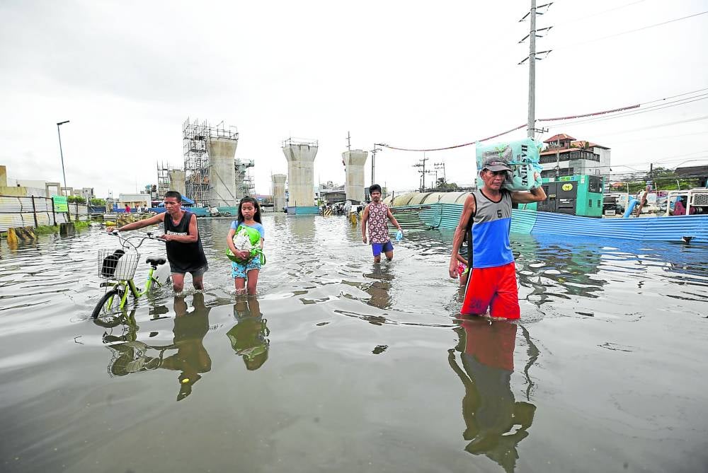 Người dân ở thị trấn Marilao thuộc tỉnh Bulacan lội qua những con đường ngập nước hôm 29.7. Ảnh: Philippine Daily Inquirer
