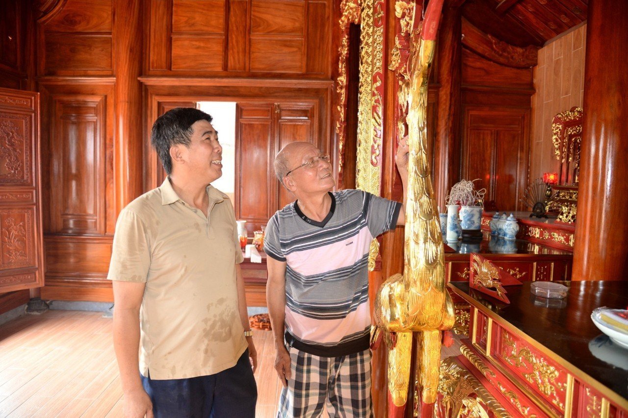 Ông Nguyễn Văn Minh (trái) giới thiệu với khách về công trình bằng gỗ mít do xưởng mộc Minh Mít thi công. Ảnh: Sỹ Thông
