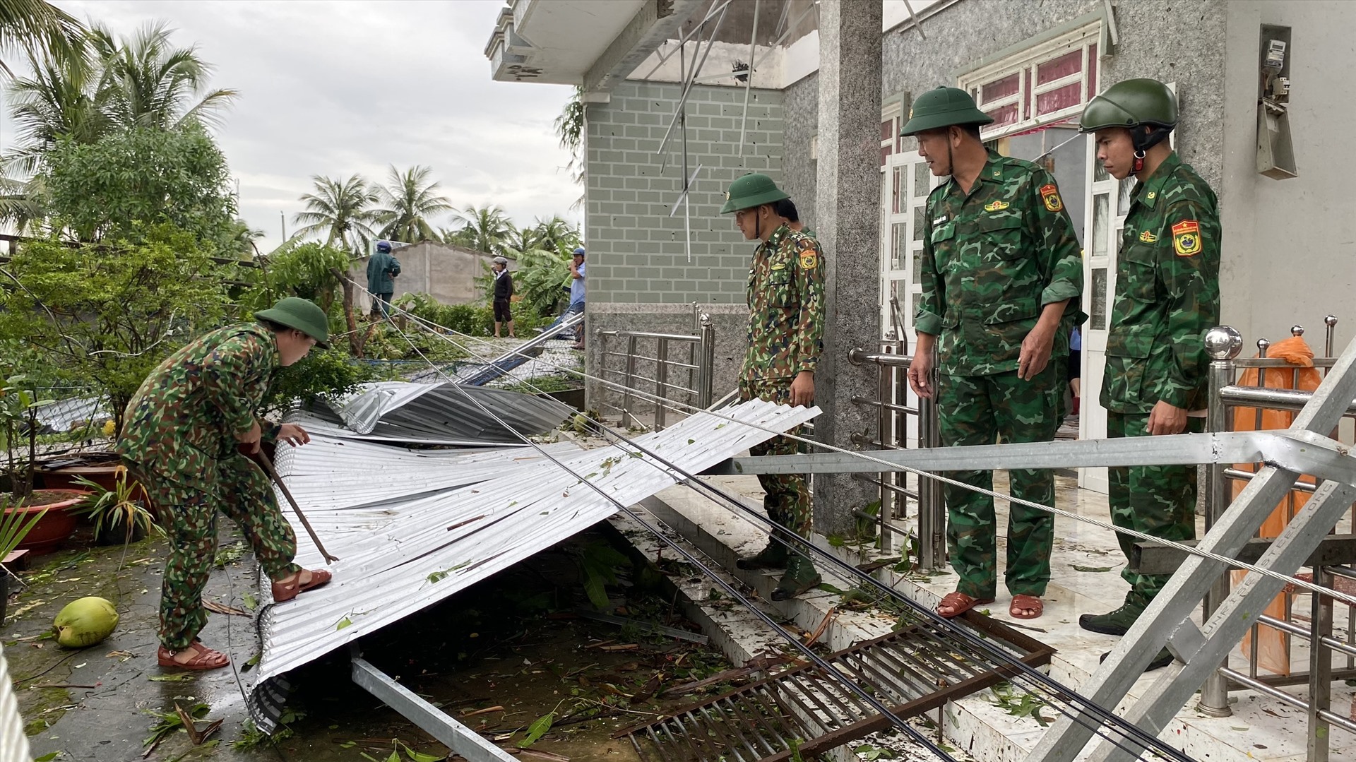 Lực lượng dân quân tự vệ, chính quyền địa phương hỗ trợ người dân dọn dẹp mái tôn bị tốc sau giông lốc