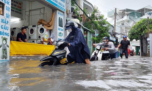 Người dân dắt xe chết máy do ngập nước trên đường Tô Ngọc Vân (thành phố Thủ Đức).  Ảnh: Minh Quân
