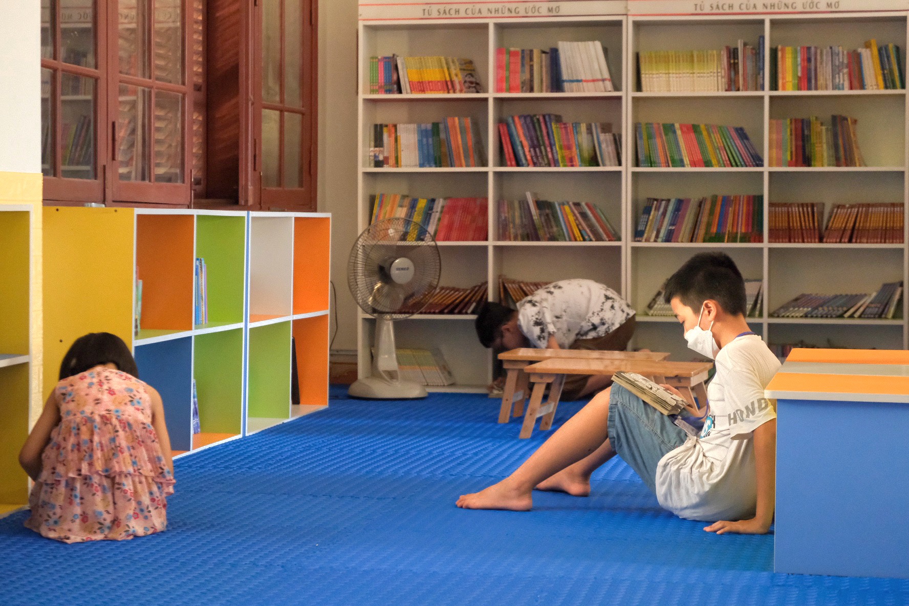 Các em nhỏ chăm chú đọc sách tại thư viện Tổng hợp tỉnh Thừa Thiên Huế, nơi hiện đang trưng bày những tác phẩm tranh vẽ trên áo dài.