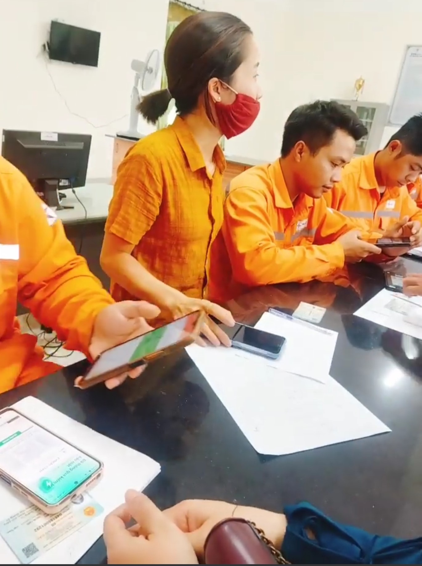 Nữ nhân viên được cho là nhân viên Bưu điện huyện Hướng Hóa mặc áo vàng, ngồi xen với nhân viên điện lực trong quá trình người dân đến làm thủ tục mua bán điện điện tử. Ảnh: Người dân cung cấp.