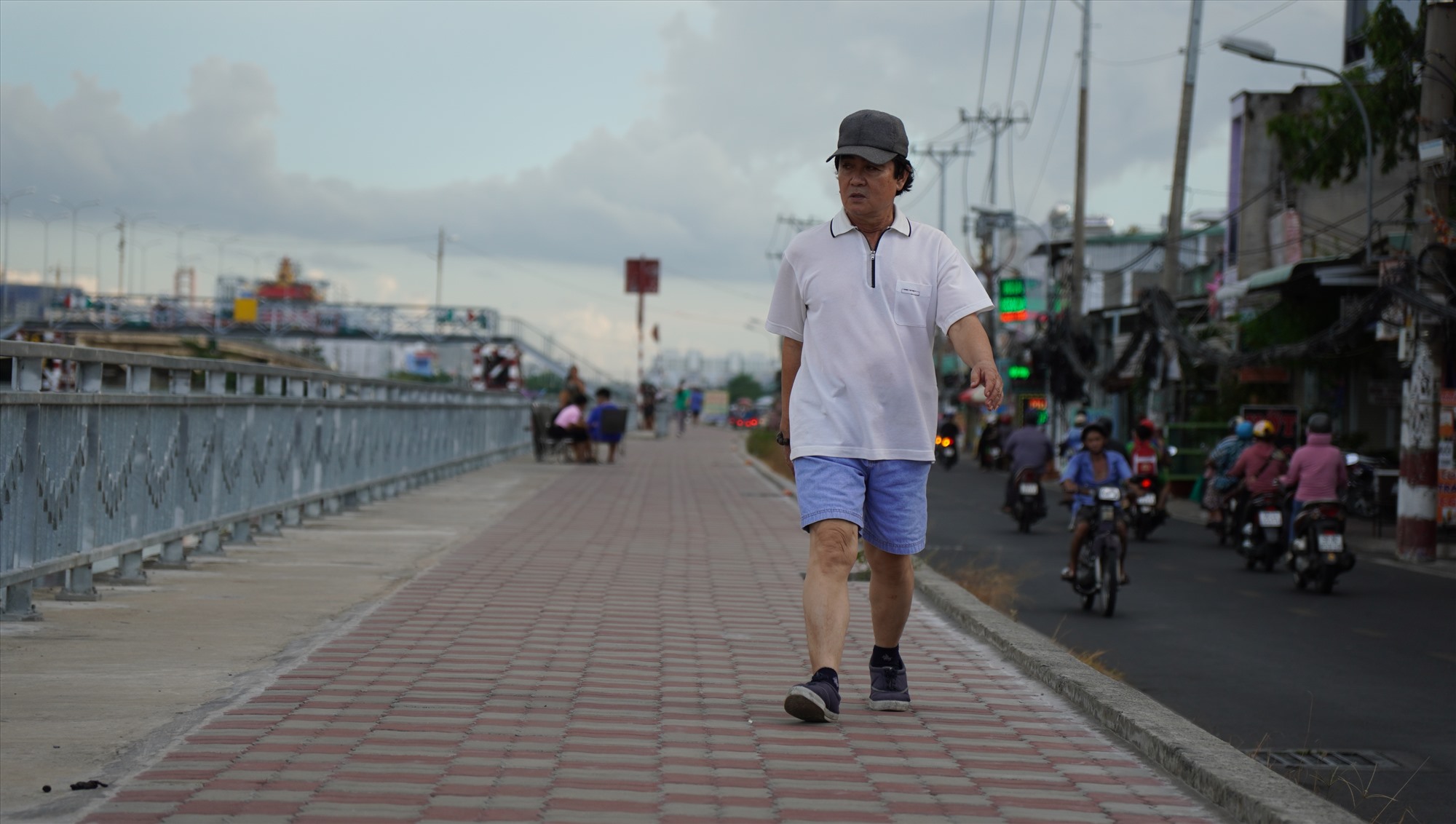 Ông Nguyễn Văn Út, 69 tuổi, sống ở bến Phú Định ra bờ kè hóng mát. Ông cho biết những năm trước khu vực này ngập nặng, nay nhờ bờ kè đã giảm nhiều.