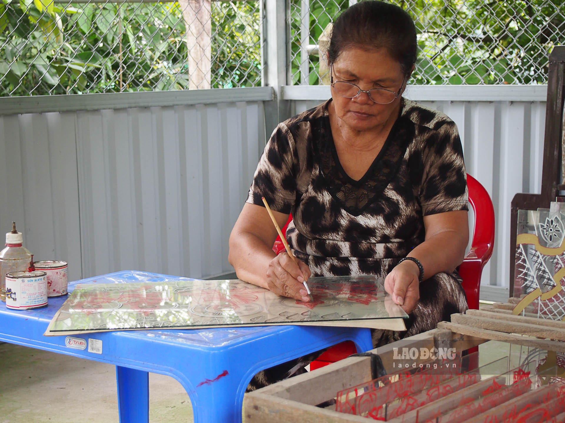 Bà Triệu Thị Vui (Phú Tân, Châu Thành, Sóc Trăng) đang vẽ tranh Phật trên kiếng. Ảnh: Phương Anh