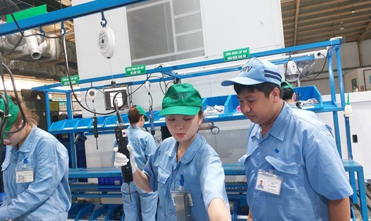 Tổ trưởng Nguyễn Quốc Việt (ngoài cùng bên phải) hướng dẫn đồng nghiệp sử dụng máy lắp ráp cầu đấu dây, đưa tấm thép hoàn toàn tự động. Ảnh: Ngọc Ánh