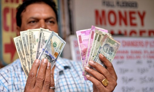 Người cầm tiền tại cửa hàng đổi tiền ở New Delhi, Ấn Độ. Ảnh: Xinhua 