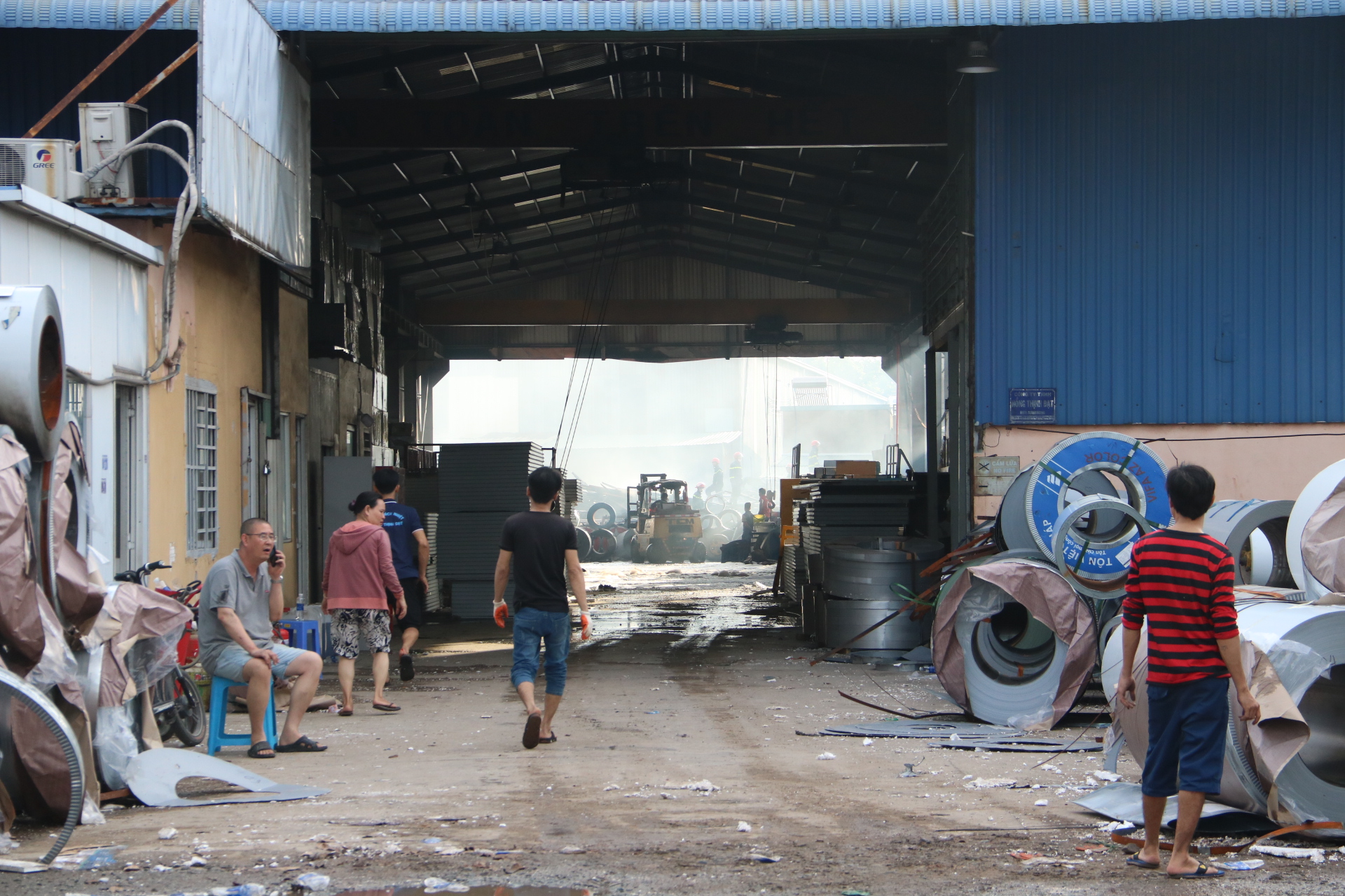Phía trước công ty bị hỏa hoạn ở đường Mỹ Phước Tân Vạn, người lao động của công ty đang di chuyển hàng hóa khắc phục thiệt hại do hỏa hoạn. 
