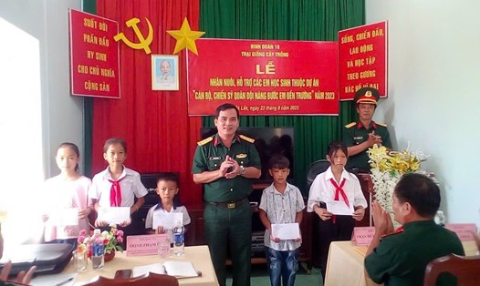 Thượng tá Trịnh Phạm Hoà, Phó chủ nhiệm Chính trị Binh đoàn 16 trao Quyết định nhận nuôi, hỗ trợ các em học sinh.  Ảnh: Hồng Thắm