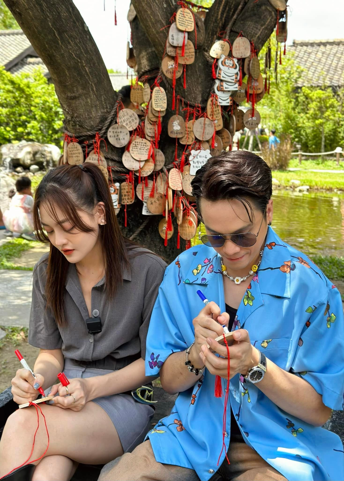 Cặp bạn thân viết điều ước lên tấm thẻ gỗ. ẢNh: FBNV.