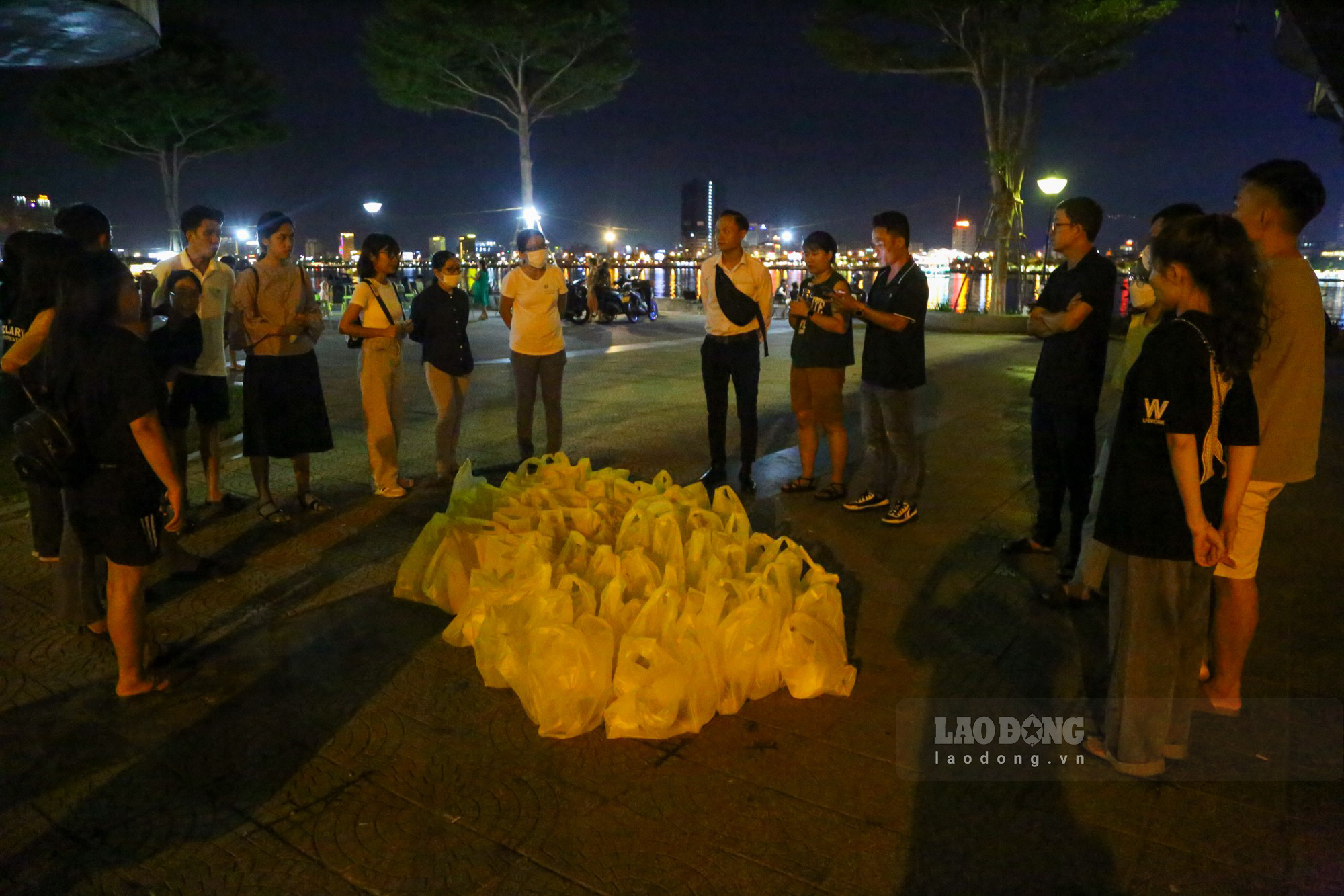 Hơn 20 giờ tối, gần 20 tình nguyện viên của chương trình “Đêm yêu thương” tập trung dưới chân cầu Rồng cùng với 80 suất ăn đêm để dành tặng cho những người lao động trên đường phố Đà Nẵng.
