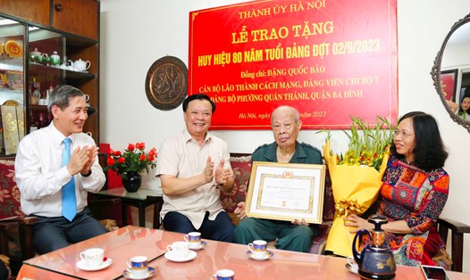 Bí thư Thành ủy Đinh Tiến Dũng trao Huy hiệu 80 năm tuổi Đảng và chúc mừng Thiếu tướng Đặng Quốc Bảo. Ảnh: Viết Thành