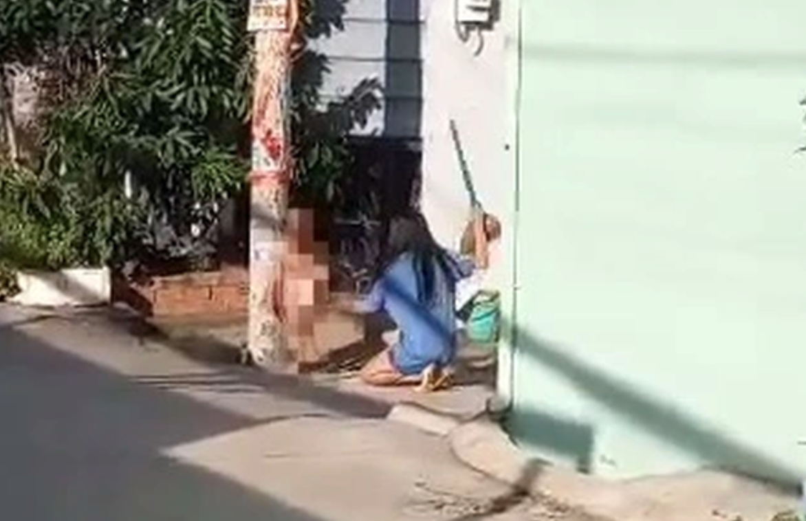 Bé trai bị hàng xóm trói vào cột điện rồi dùng chối đánh vào người. Ảnh: Cắt từ clip của người dân